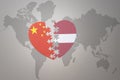 Puzzle heart with the national flag of china and latvia on a world map background. Concept Royalty Free Stock Photo
