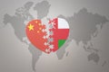 Puzzle heart with the national flag of china and oman on a world map background. Concept Royalty Free Stock Photo