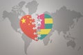 Puzzle heart with the national flag of china and togo on a world map background. Concept Royalty Free Stock Photo