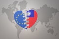 Puzzle heart with the national flag of european union and taiwan on a world map background. Concept Royalty Free Stock Photo