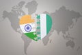Puzzle heart with the national flag of india and nigeria on a world map background.Concept Royalty Free Stock Photo