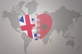 Puzzle heart with the national flag of morocco and great britain on a world map background. Concept