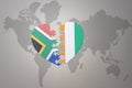 Puzzle heart with the national flag of south africa and cote divoire on a world map background. 3D illustration