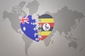 Puzzle heart with the national flag of uganda and australia on a world map background. Concept Royalty Free Stock Photo