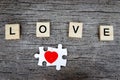 Puzzle jigsaw forming red heart and text wooden blocks spelling the word LOVE and on rustic brown wooden surface, romantic Royalty Free Stock Photo