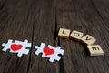 Puzzle jigsaw forming red heart and text wooden blocks spelling the word LOVE and on rustic brown wooden surface, romantic Royalty Free Stock Photo