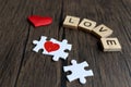 Puzzle jigsaw forming red heart and text wooden blocks spelling the word LOVE and on rustic brown wooden surface, romantic Royalty Free Stock Photo