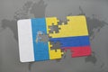 puzzle with the national flag of canary islands and colombia on a world map background.