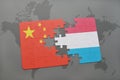 puzzle with the national flag of china and luxembourg on a world map background.