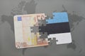 puzzle with the national flag of estonia and euro banknote on a world map background. Royalty Free Stock Photo