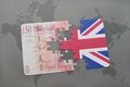 puzzle with the national flag of great britain and british pound on a world map background.