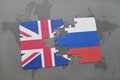 Puzzle with the national flag of great britain and russia on a world map background