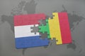 puzzle with the national flag of netherlands and mali on a world map background. Royalty Free Stock Photo