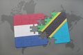 puzzle with the national flag of netherlands and tanzania on a world map background. Royalty Free Stock Photo