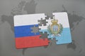 puzzle with the national flag of russia and san marino on a world map background. Royalty Free Stock Photo