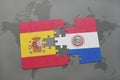 puzzle with the national flag of spain and paraguay on a world map background.