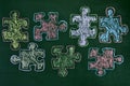 Puzzle pieces of different colors drawn on a chalkboard, as the