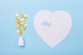 Puzzle in shape of heart white and yellow pills on blue background Jigsaw Concept treatment of heart disease pills Royalty Free Stock Photo