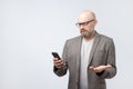 Puzzled bald man reading sms with emotional face expression