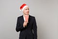 Puzzled business man in Christmas hat looking up, drinking soda from plastic cup isolated on grey background Royalty Free Stock Photo