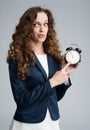 Puzzled business woman holding an alarm clock