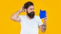 puzzled guy with present isolated on yellow background. present box for guy in shirt.