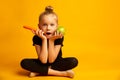 Puzzled little dancer choosing between a green apple and a carrot