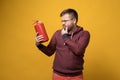 Puzzled man with glasses holds a fire extinguisher in hand and looks at it thoughtfully. Yellow background. Royalty Free Stock Photo