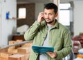 Puzzled man standing with papers in house during renovation