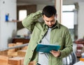 Puzzled man standing with papers in house during renovation