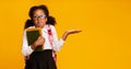 Puzzled School Girl Shrugging Shoulders Holding Books On Yellow Background Royalty Free Stock Photo