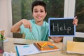 Puzzled schoolboy holds a blackboard HELP, points his finger at a notebook with examples of math and geometry