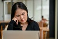 Puzzled and stressed Asian woman is looking down at her laptop screen with a serious face Royalty Free Stock Photo