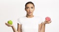 Puzzled Woman Holding Apple And Doughnut Choosing, Studio Shot, Panorama Royalty Free Stock Photo