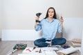 Puzzled woman sitting on the floor with a screwdriver and electric screwdriver in hand, furniture Assembly Royalty Free Stock Photo