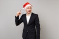 Puzzled young business man pointing index finger on Christmas hat on head isolated on grey wall background. Achievement Royalty Free Stock Photo