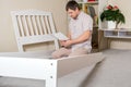 A puzzled young father assembles a bed for a child, studies the instructions for assembling furniture with his own hands