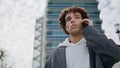 Puzzled youngster calling cellphone at urban settings. Young man waiting friend Royalty Free Stock Photo