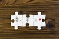 Puzzles with the image of a couple, hearts on a wooden background.