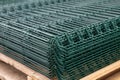 PVC Coated Curvy Welded Fence on warehouse. Building materials. Green sections of wire mesh for fencing on racks