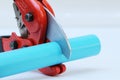 PVC water pipe cutter with red metal body, black rubber handle and sharp thick blade on white background.