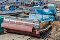 Sections from damaged fishing trawlers in sun at small port