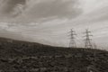 Pylons overhead power lines on mountain and cloudy sky Royalty Free Stock Photo