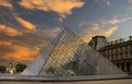 Pyramid of the Louvre museum in Paris at sunset under an orange sky and on the banks of the Seine river Royalty Free Stock Photo