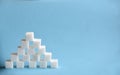 Pyramid made from cubes of refined white sugar on blue background. Copy space Royalty Free Stock Photo