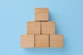 Pyramid made of wooden cubes on light blue background, top view. Management concept Royalty Free Stock Photo