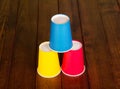 Pyramid from multi-colored disposable cups on background dark wood. Royalty Free Stock Photo