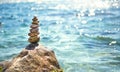 A pyramid of pebbles on a large stone against the background of the sea and the sun`s glare on the water. Tour, tourism, vacation Royalty Free Stock Photo