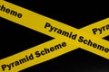 Pyramid scheme alert, caution and warning concept. Yellow barricade tape with word scam in dark black background. Royalty Free Stock Photo