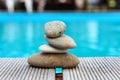 Pyramid of sea pebbles on the edge of the pool and against the background of gazebos for relaxation. The concept of life balance Royalty Free Stock Photo